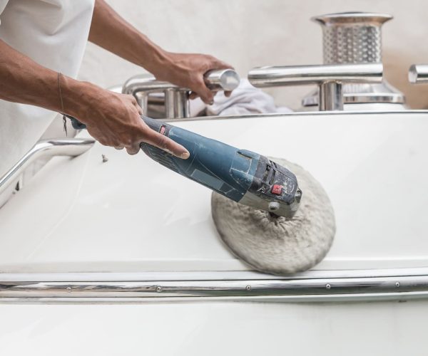 Polissage yacht Homme en train de faire du polissage sur la coque d'un Yacht